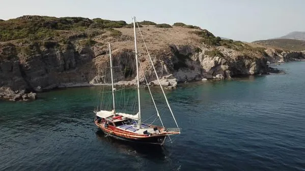Trİppİn Yacht Photos Pics Wooden Ketch Tirhandil 20M sailing near rocky coastline, 2006 model.
