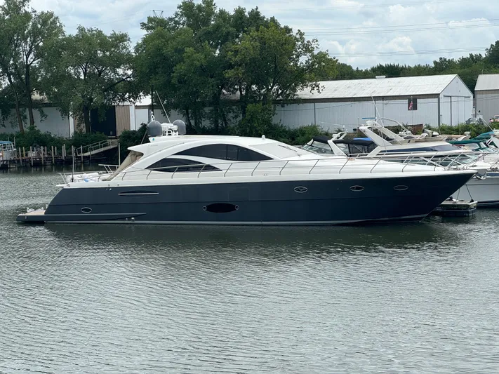  Yacht Photos Pics 2007 Uniesse 70 Sport yacht docked on calm water, surrounded by trees and buildings.