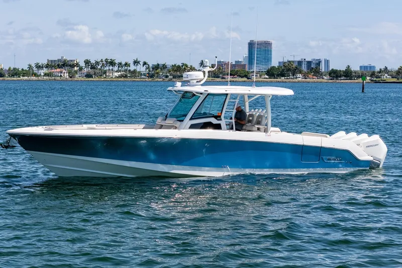  Yacht Photos Pics 2022 Boston Whaler 380 Outrage boat cruising on calm waters near a city skyline.