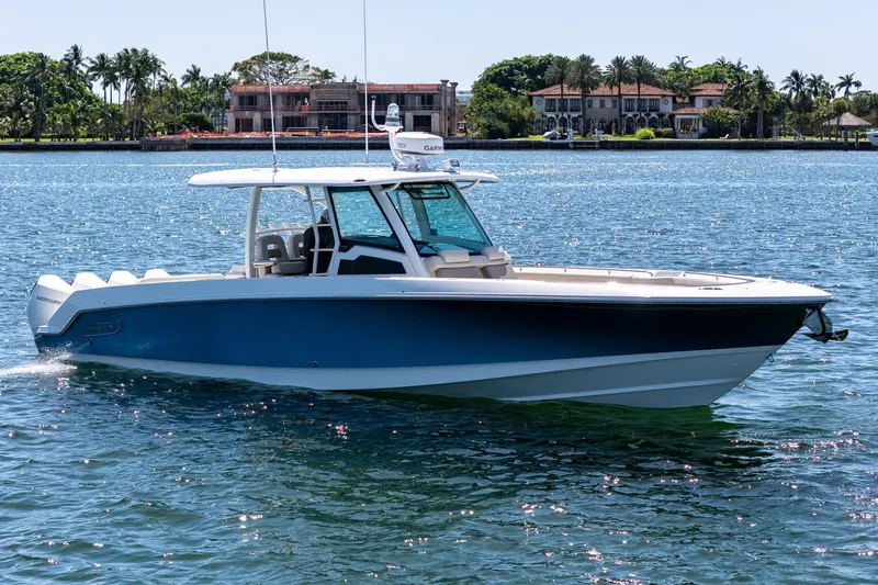  Yacht Photos Pics 2022 Boston Whaler 380 Outrage boat cruising on a sunny day near luxury waterfront homes.
