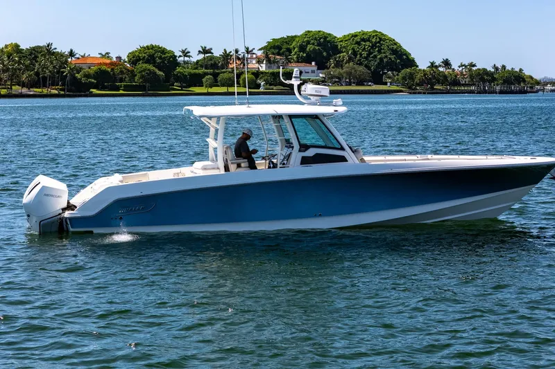  Yacht Photos Pics 2022 Boston Whaler 380 Outrage boat cruising on a sunny day near lush shoreline.