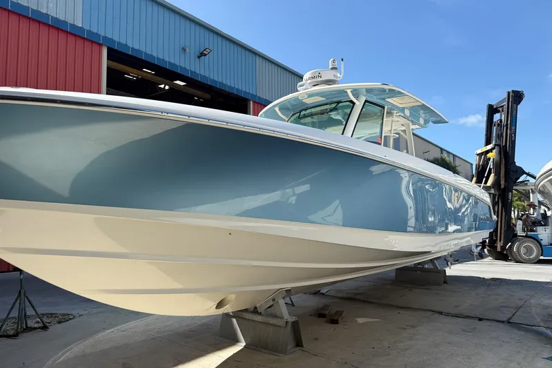  Yacht Photos Pics 2022 Boston Whaler 380 Outrage boat in a marina, showcasing sleek design and blue hull.