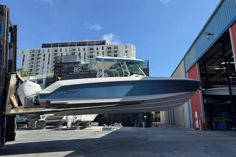  Yacht Photos Pics 2022 Boston Whaler 380 Outrage boat lifted in marina, urban backdrop.