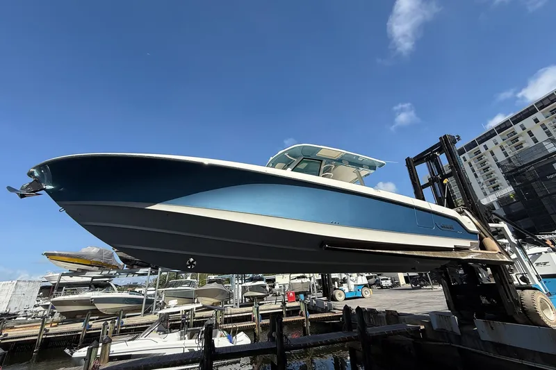  Yacht Photos Pics 2022 Boston Whaler 380 Outrage boat lifted at marina under clear blue sky.