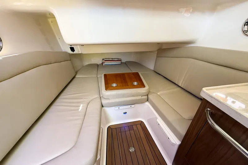  Yacht Photos Pics 2022 Boston Whaler 380 Outrage cabin interior with cushioned seating and wooden table.