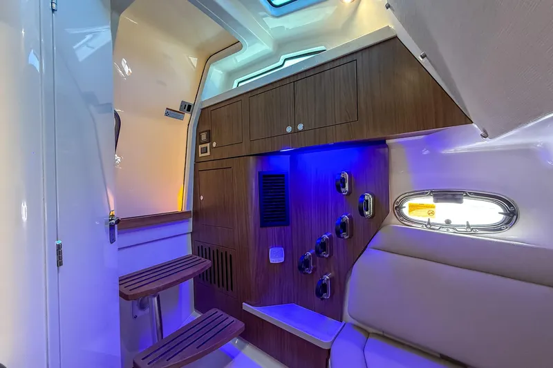  Yacht Photos Pics 2022 Boston Whaler 380 Outrage cabin interior with wood accents and ambient lighting.