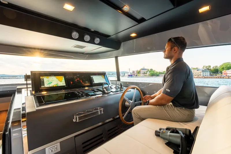 North Yacht Photos Pics Man piloting 2020 Sanlorenzo SX88 yacht with advanced navigation system at sunset.