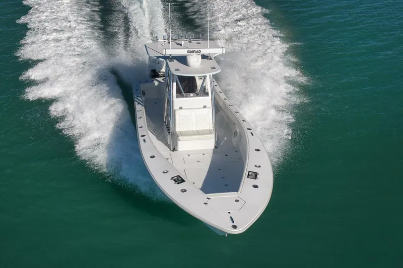  Yacht Photos Pics 2025 Conch 27 boat cruising on clear blue water, creating a dynamic wake.