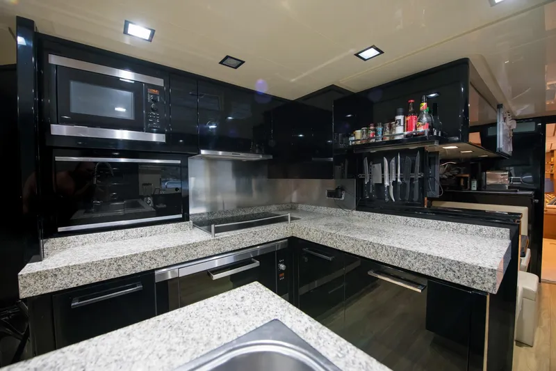 La Rubia Yacht Photos Pics Modern kitchen interior on 2011 Azimut La Rubia yacht, featuring sleek black cabinetry and granite countertops.