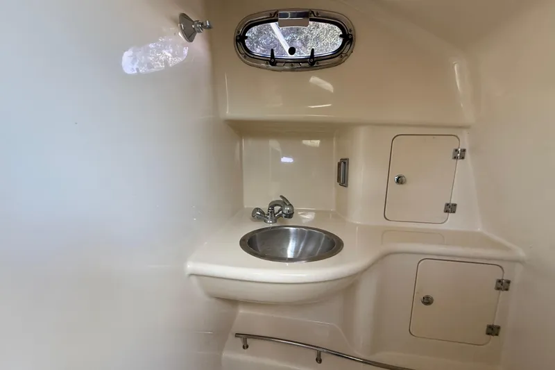  Yacht Photos Pics 2011 Boston Whaler 285 Conquest bathroom with sink, storage cabinets, and porthole window.