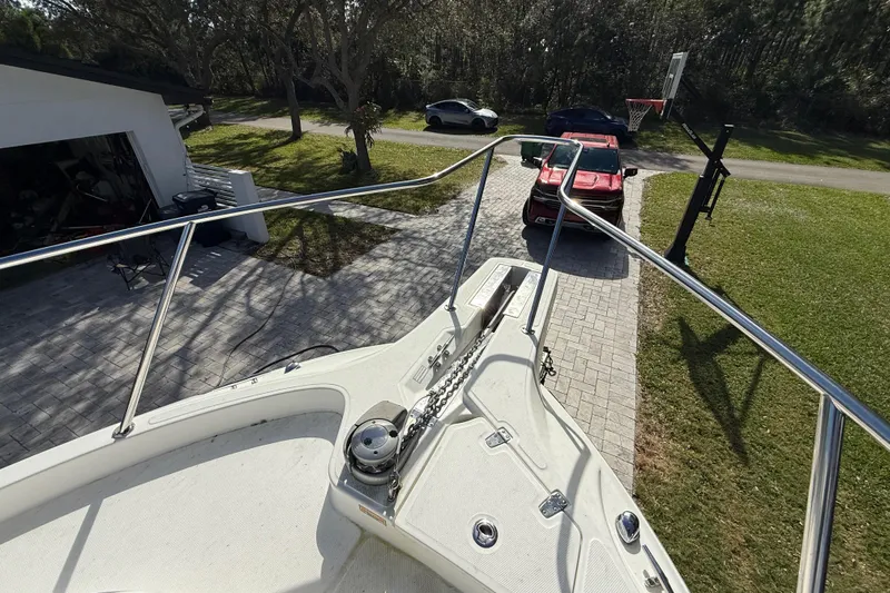  Yacht Photos Pics 2011 Boston Whaler 285 Conquest boat on driveway, surrounded by trees and vehicles.