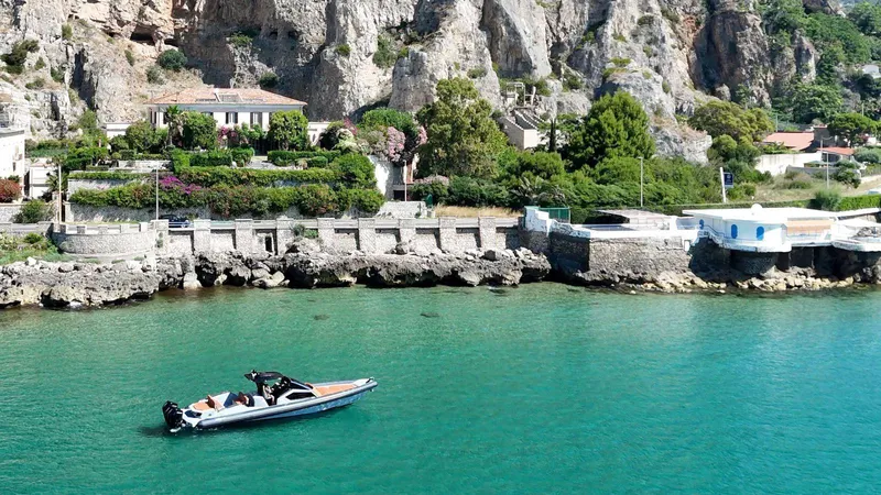  Yacht Photos Pics Luxury DNA 46 boat cruising near rocky coastline with lush greenery, 2025 model.