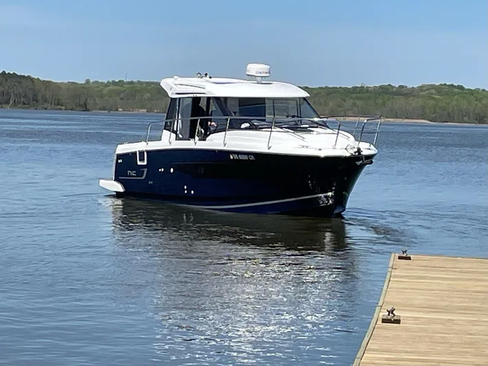 Sapphire Yacht Photos Pics 2020 Jeanneau NC 895 boat on calm water near a wooden dock.