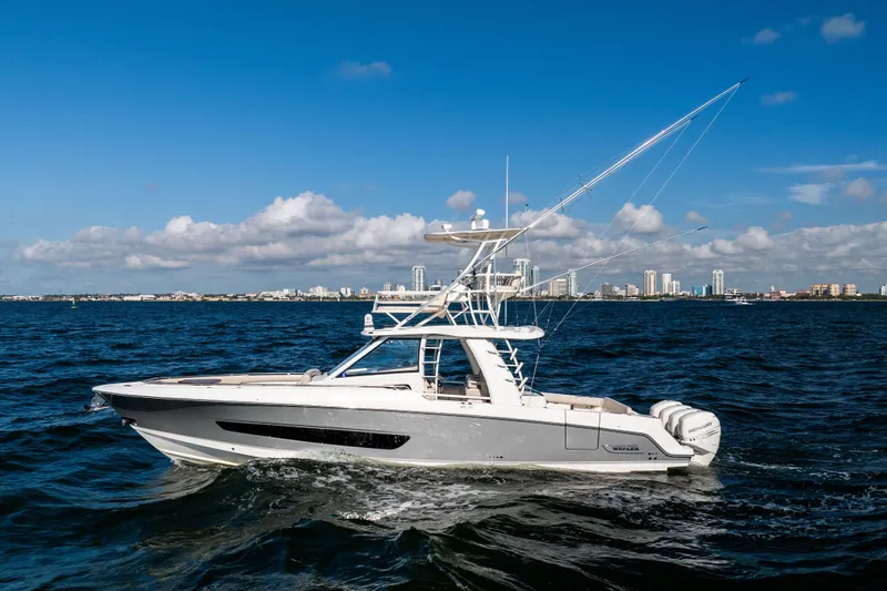 Smoke Show Yacht Photos Pics 2021 Boston Whaler 420 Outrage cruising on open water with city skyline backdrop.