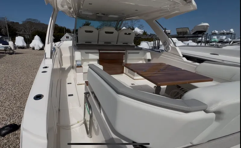  Yacht Photos Pics 2023 Tiara Yachts 38 LS interior with seating and wooden table, docked outdoors.