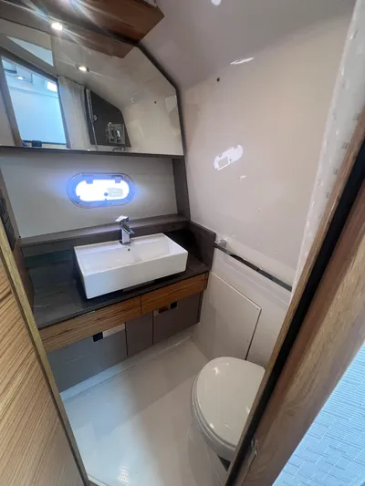  Yacht Photos Pics 2023 Tiara Yachts 38 LS bathroom with modern sink, toilet, and porthole window.