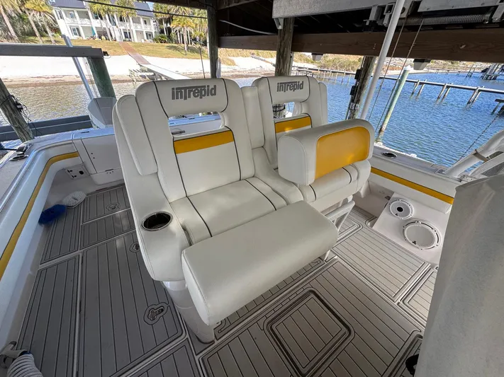  Yacht Photos Pics 2020 Intrepid 407 Cuddy boat interior with white and yellow seating, docked by the water.