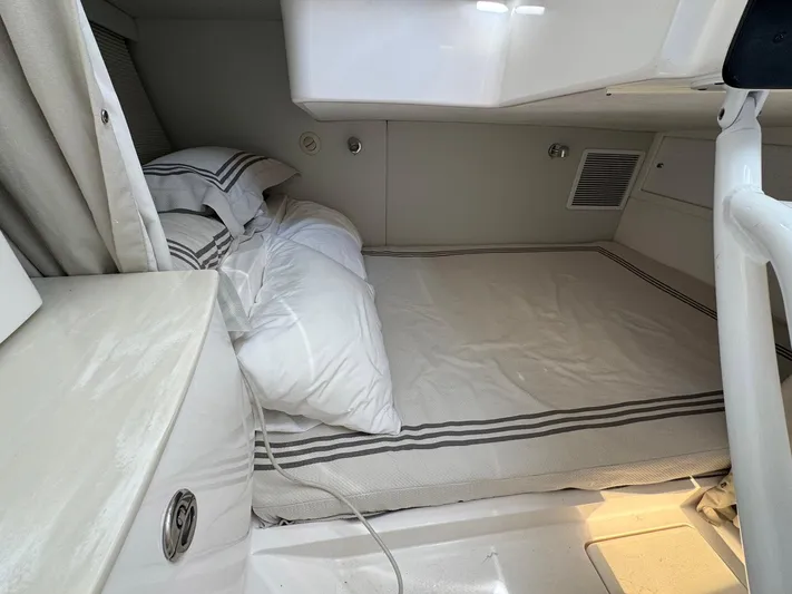  Yacht Photos Pics 2020 Intrepid 407 Cuddy cabin interior with neatly arranged bed and striped bedding.