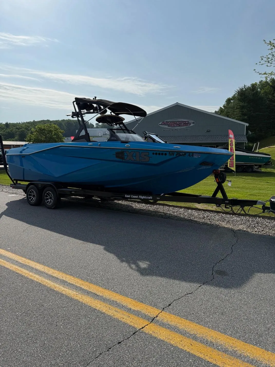 2022 Axis T250 boat in blue on a trailer, parked on a sunny road.