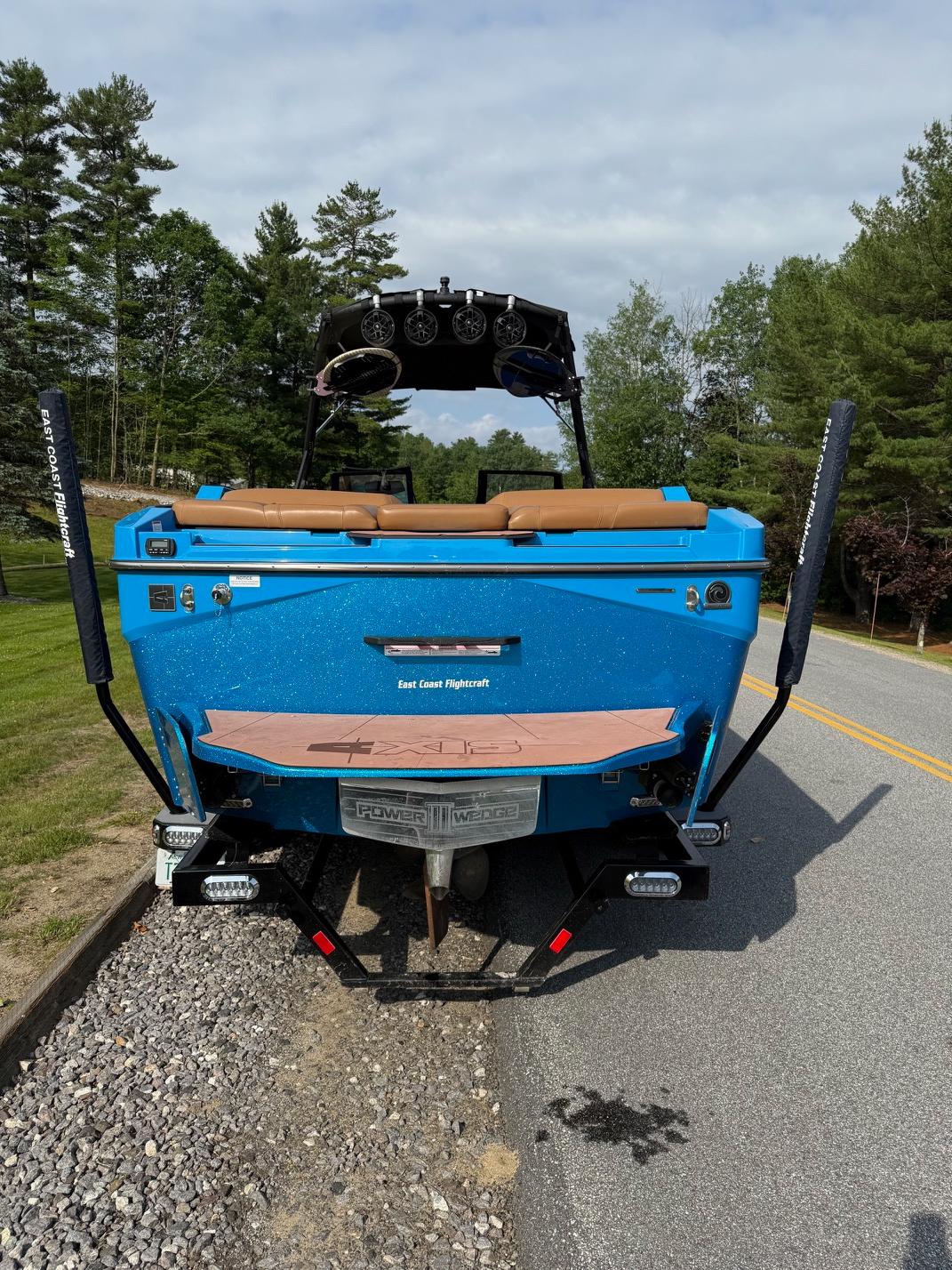 2022 Axis T250 boat, blue exterior, parked on roadside with trees in background.