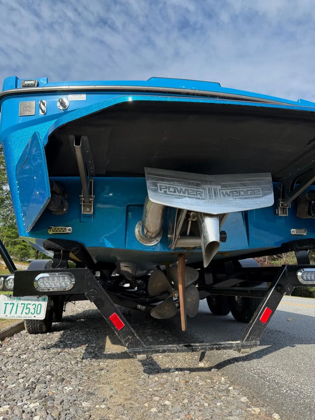 Rear view of a blue 2022 Axis T250 boat on a trailer, showcasing the propeller and exhaust.