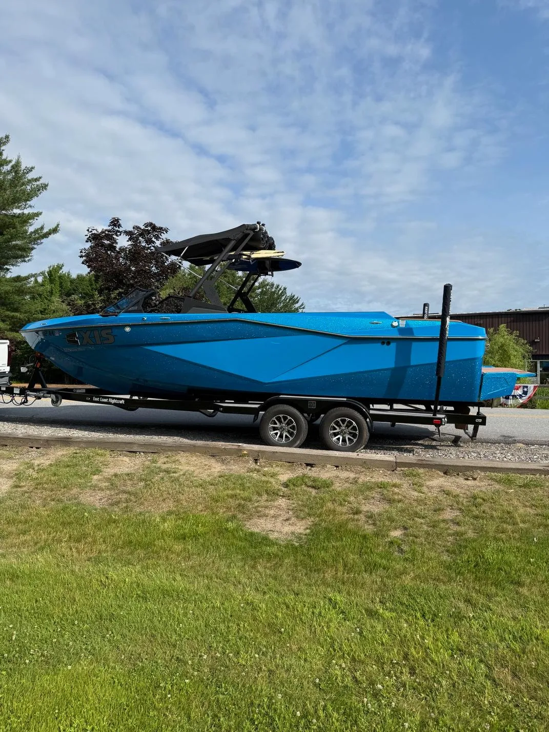 Blue 2022 Axis T250 boat on trailer, parked outdoors under a partly cloudy sky.