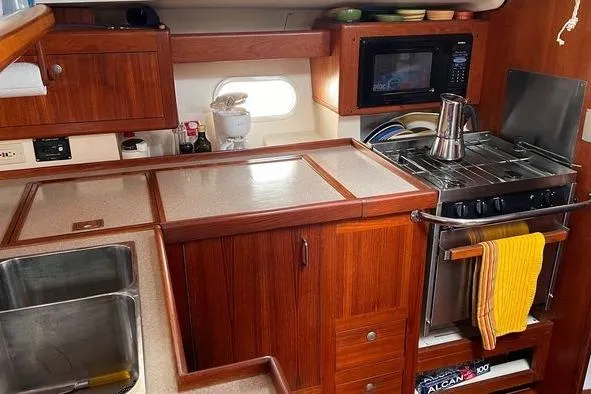  Yacht Photos Pics 1999 Hunter 410 yacht kitchen with wooden cabinetry, stove, and microwave.