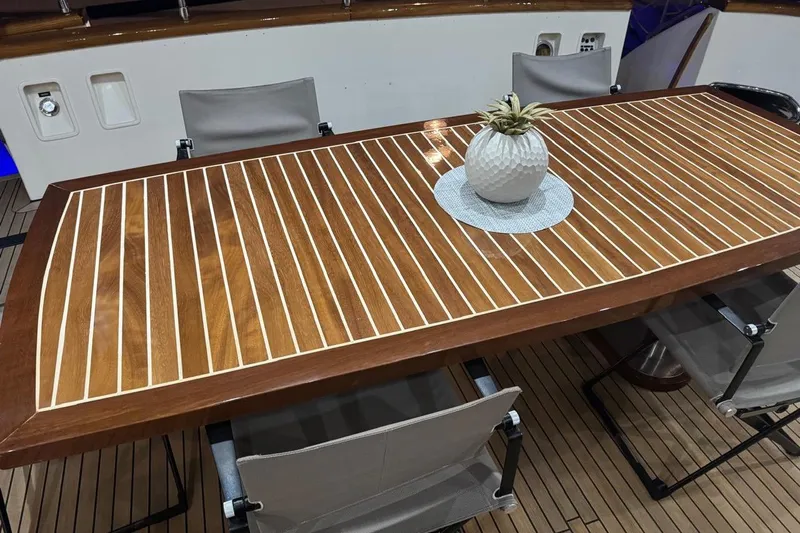 My Sons Yacht Photos Pics Elegant wooden table with striped design on a Falcon 86 yacht, featuring a decorative plant centerpiece.