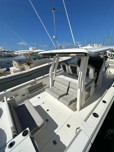  Yacht Photos Pics 2023 Pursuit S 358 Sport boat with spacious seating, docked under clear blue skies.