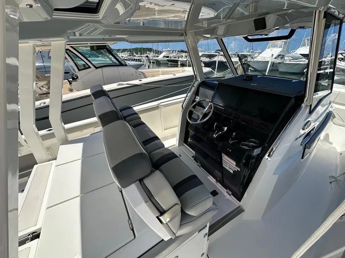  Yacht Photos Pics 2023 Pursuit S 358 Sport boat interior with helm and seating, docked at marina.