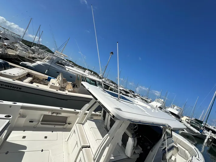  Yacht Photos Pics 2023 Pursuit S 358 Sport boat docked in a marina under clear blue skies.