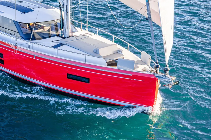In Stock - W / Warranty Yacht Photos Pics 2024 Moody 41ds sailboat with vibrant red hull sailing on blue ocean waters.