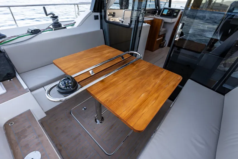 In Stock - W / Warranty Yacht Photos Pics 2024 Moody 41ds yacht interior with wooden table and compass, overlooking the sea.