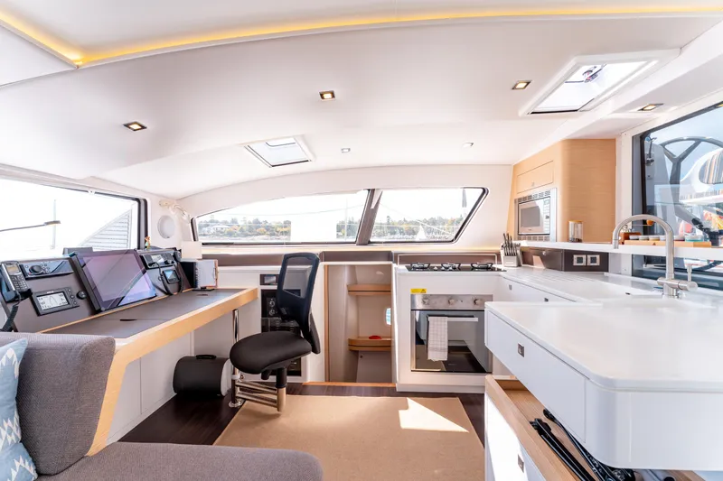 Wikiwiki Yacht Photos Pics Modern interior of 2018 Outremer 5X yacht featuring navigation station and kitchen area.