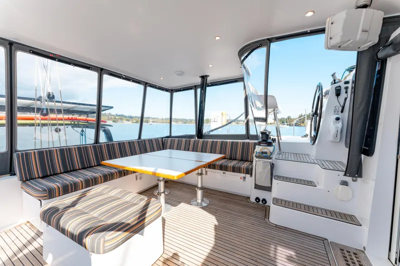 Wikiwiki Yacht Photos Pics Interior of 2018 Outremer 5X catamaran with striped seating and a central table.