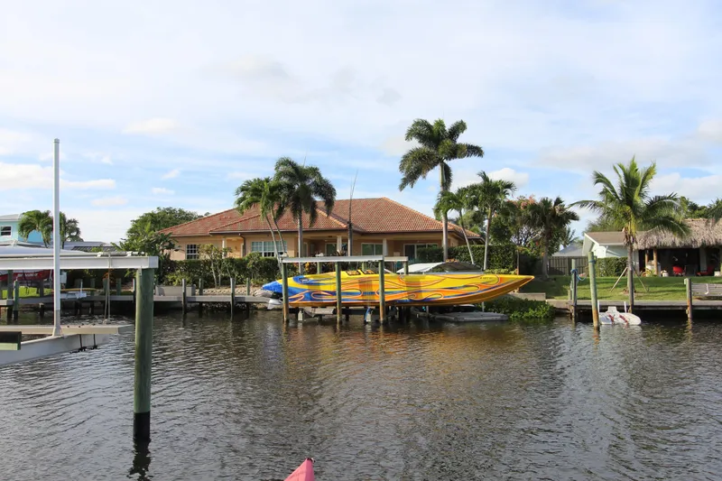  Yacht Photos Pics Tropical waterfront home with 2007 MTI 40RP speedboat docked, surrounded by palm trees.