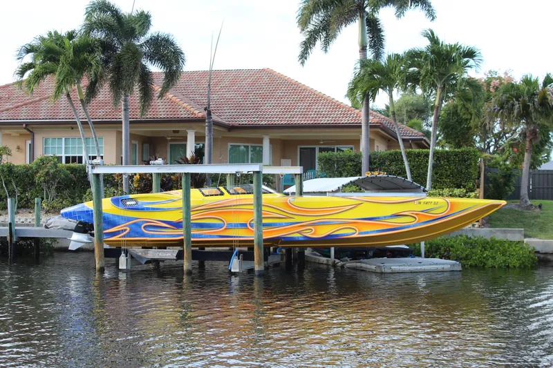  Yacht Photos Pics Colorful 2007 MTI 40RP speedboat docked by waterfront home with palm trees.