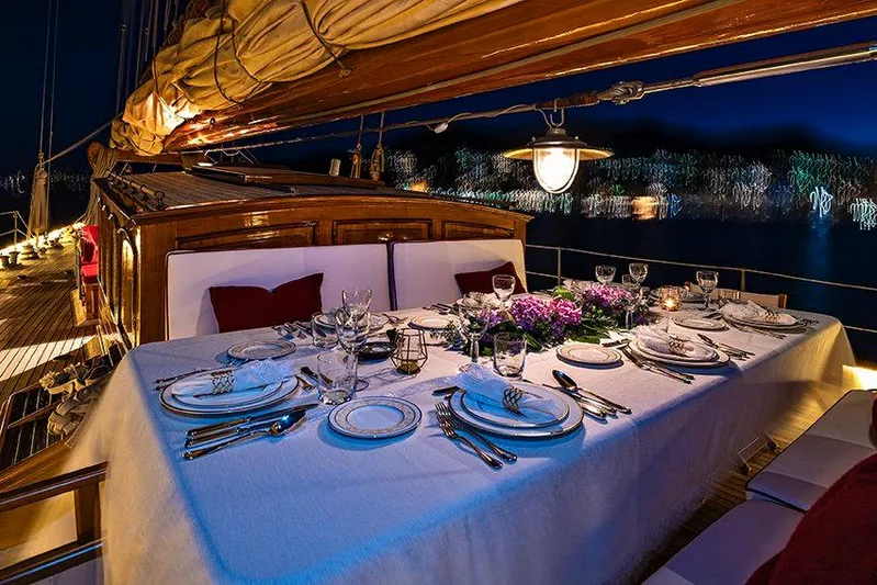 Invader Yacht Photos Pics Elegant dining setup on 1905 Lawley Schooner, illuminated at night.