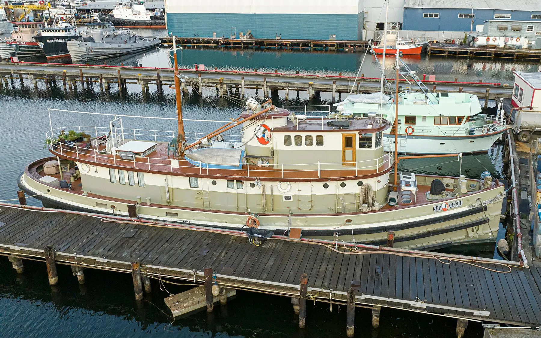 Vintage 1943 Custom Navy Tugboat docked at a marina, surrounded by other vessels.