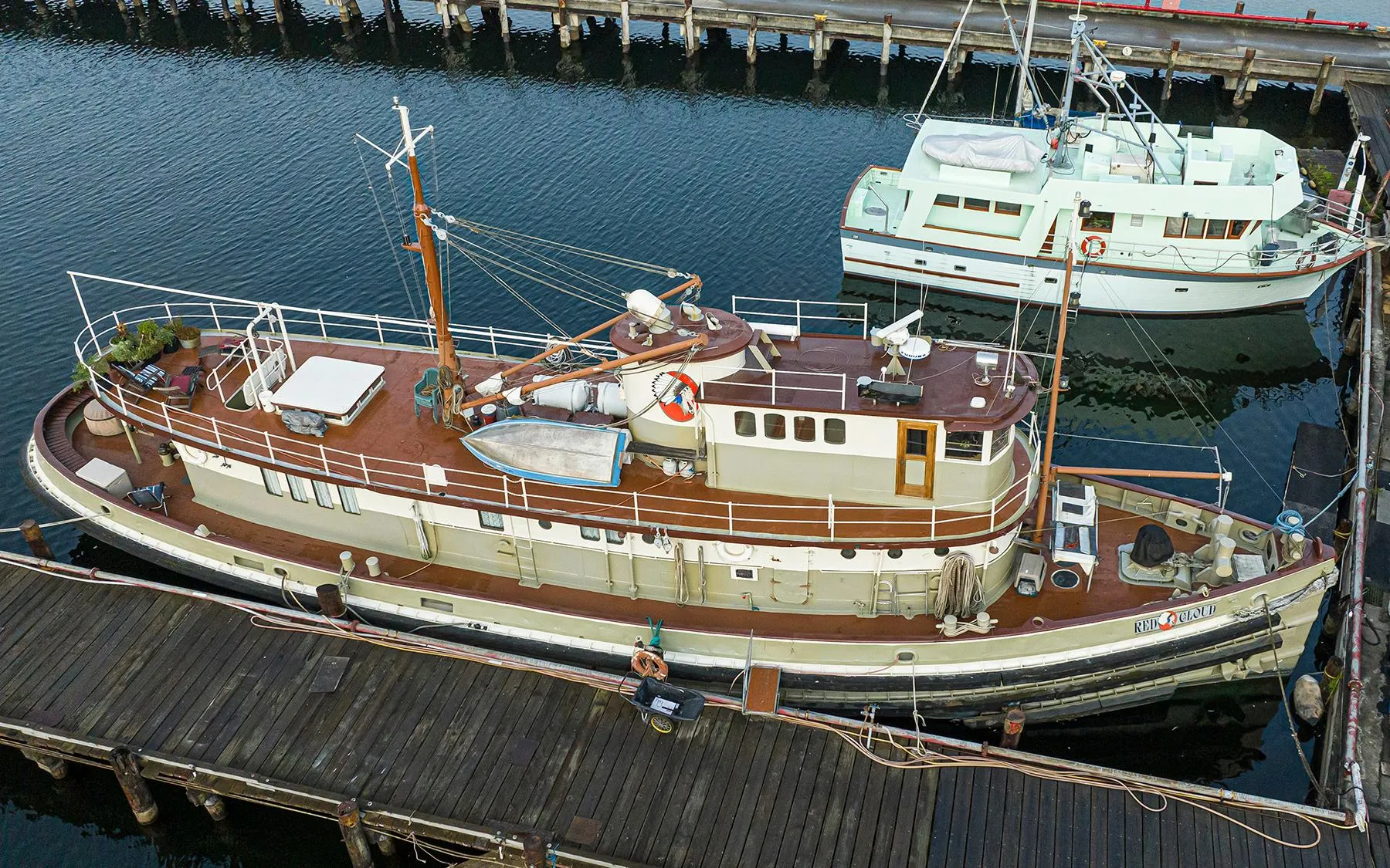 Custom 1943 Navy Tugboat docked at a marina, with a vintage design and wooden deck.
