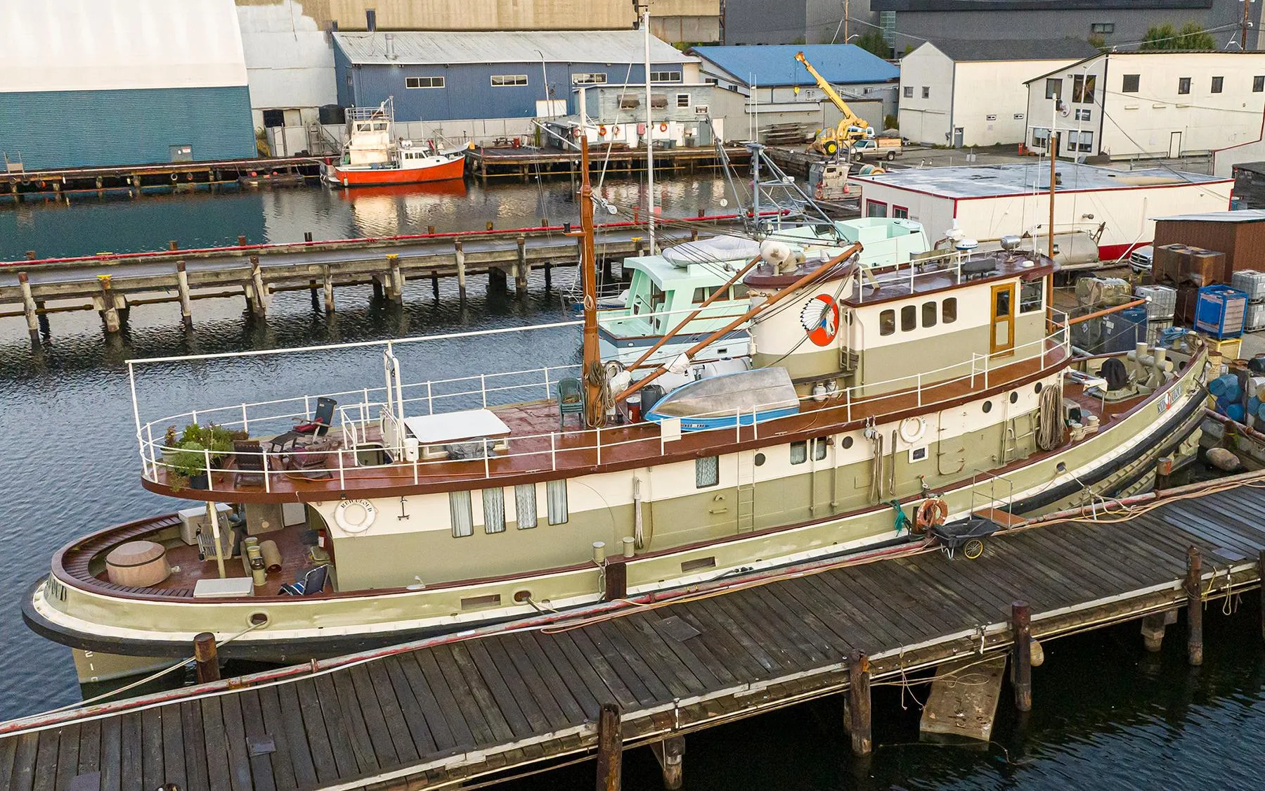 Historic 1943 Custom Navy Tugboat docked at a marina, surrounded by industrial buildings.