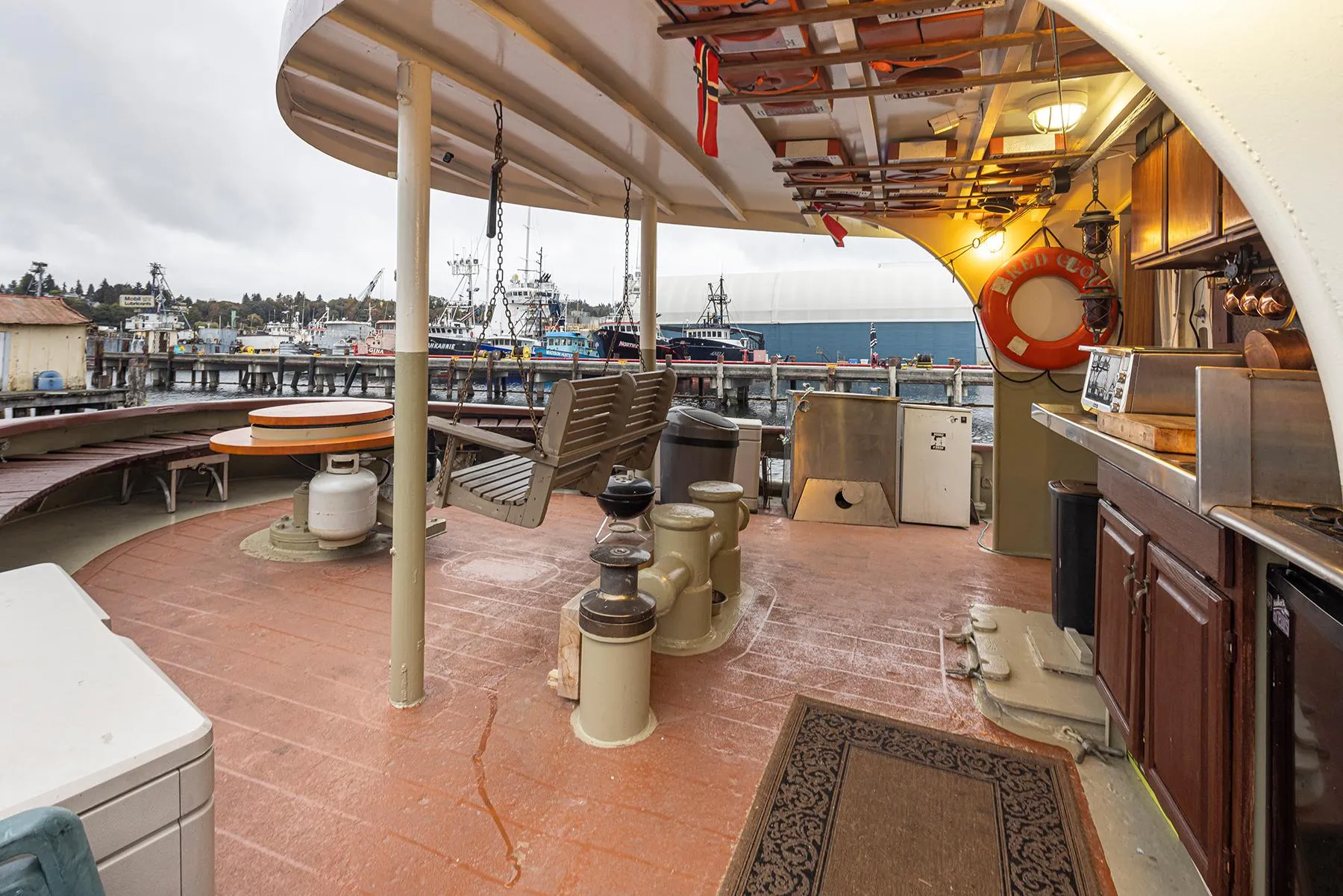 1943 Custom Navy Tugboat deck with seating, kitchen area, and harbor view.
