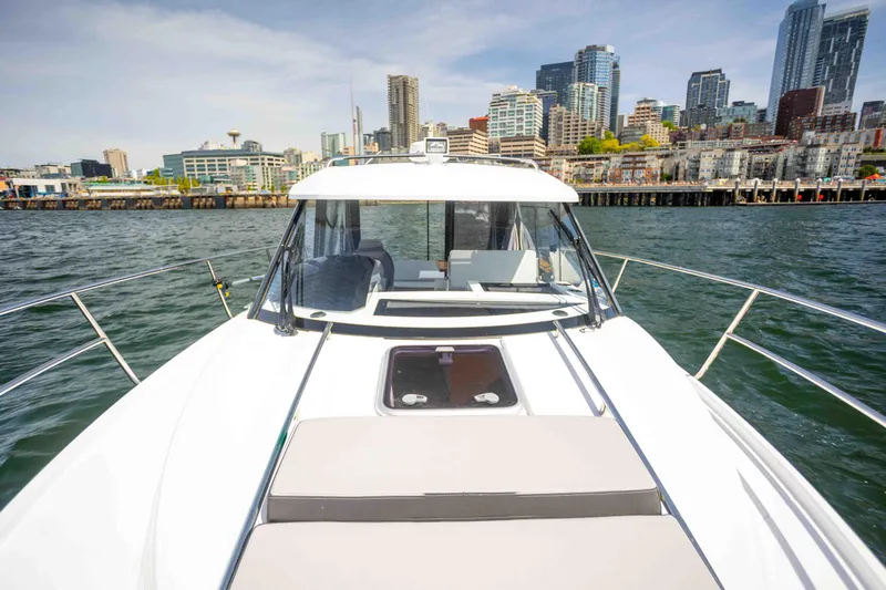  Yacht Photos Pics 2022 Jeanneau NC Weekender 895 on water with city skyline in background.