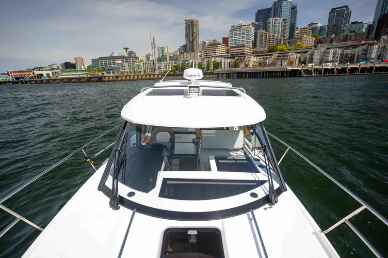  Yacht Photos Pics 2022 Jeanneau NC Weekender 895 on water with city skyline in background.