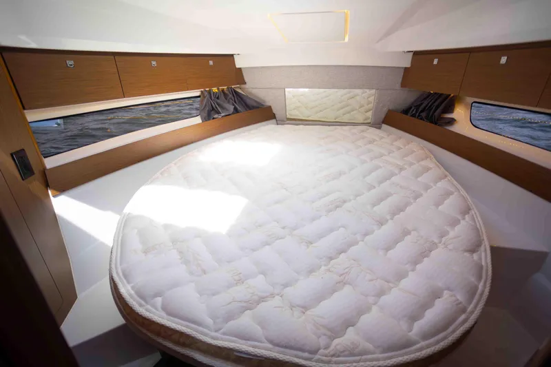  Yacht Photos Pics 2022 Jeanneau NC Weekender 895 cabin with a spacious round bed and wooden storage cabinets.