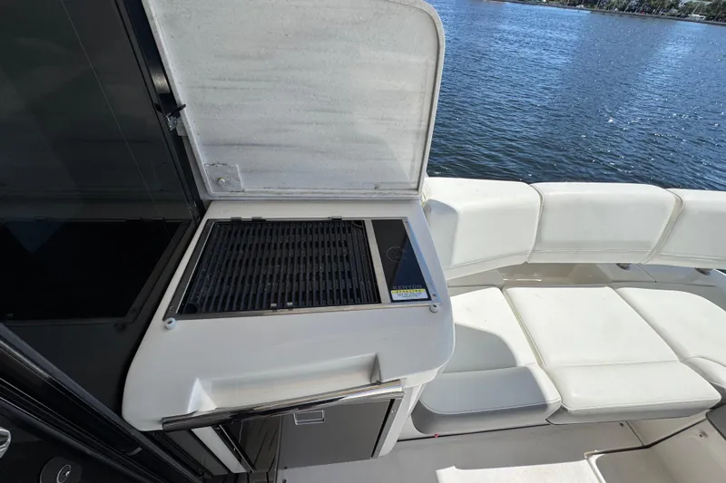 Carchi Yacht Photos Pics Outdoor grill and seating area on 2022 Regal 42 XO yacht by the water.