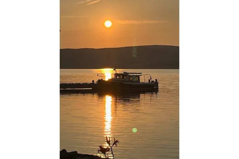 Mystic Yacht Photos Pics 2014 Ranger Tugs R-31 boat silhouetted against a serene sunset on a calm lake.