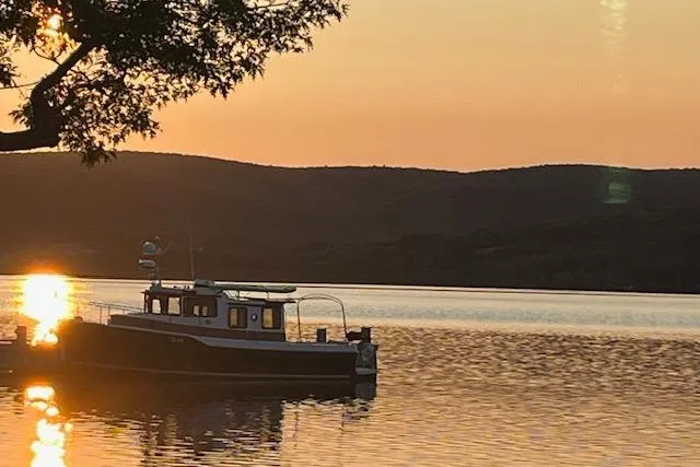 Mystic Yacht Photos Pics 2014 Ranger Tugs R-31 boat on serene lake at sunset, silhouetted by hills and tree.