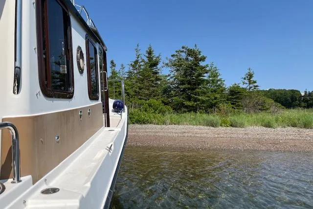 Mystic Yacht Photos Pics 2014 Ranger Tugs R-31 boat near a scenic shoreline with trees and clear blue sky.