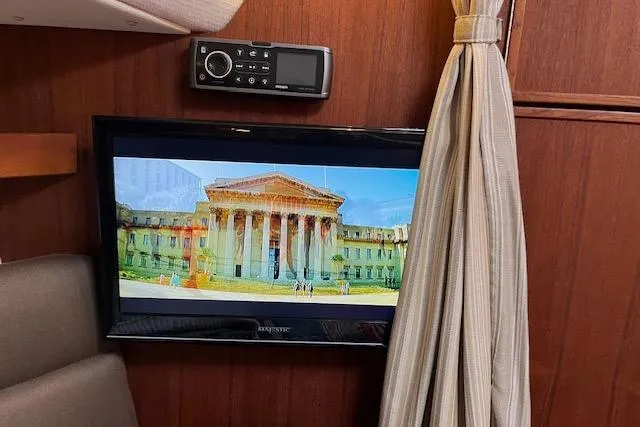 Mystic Yacht Photos Pics Interior of 2014 Ranger Tugs R-31 with TV displaying a building, wood paneling, and curtain.